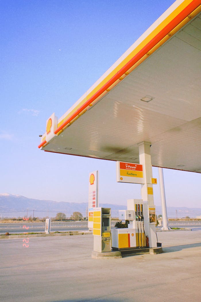 Sunlit view of an empty gas station with clear skies and mountains in the background.