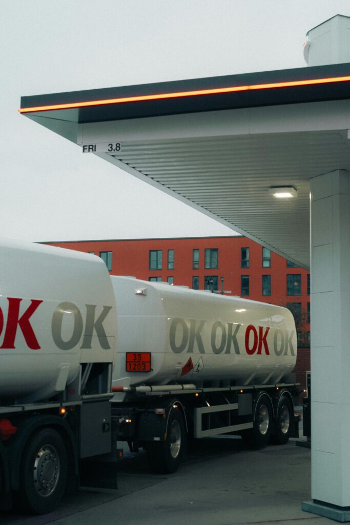 pexels-photo-30115404-30115404 A fuel tanker truck refueling at a contemporary gas station with urban backdrop.