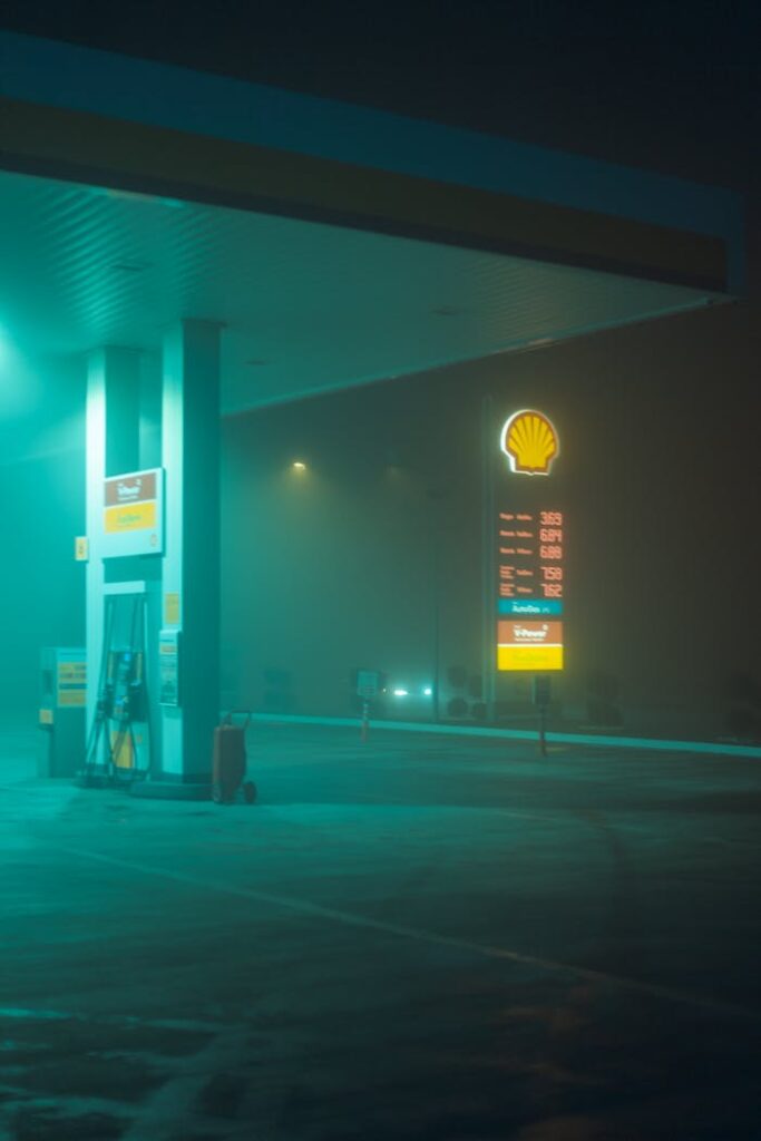 pexels-photo-7382516 Mysterious foggy night view of a deserted gas station under vibrant lights.